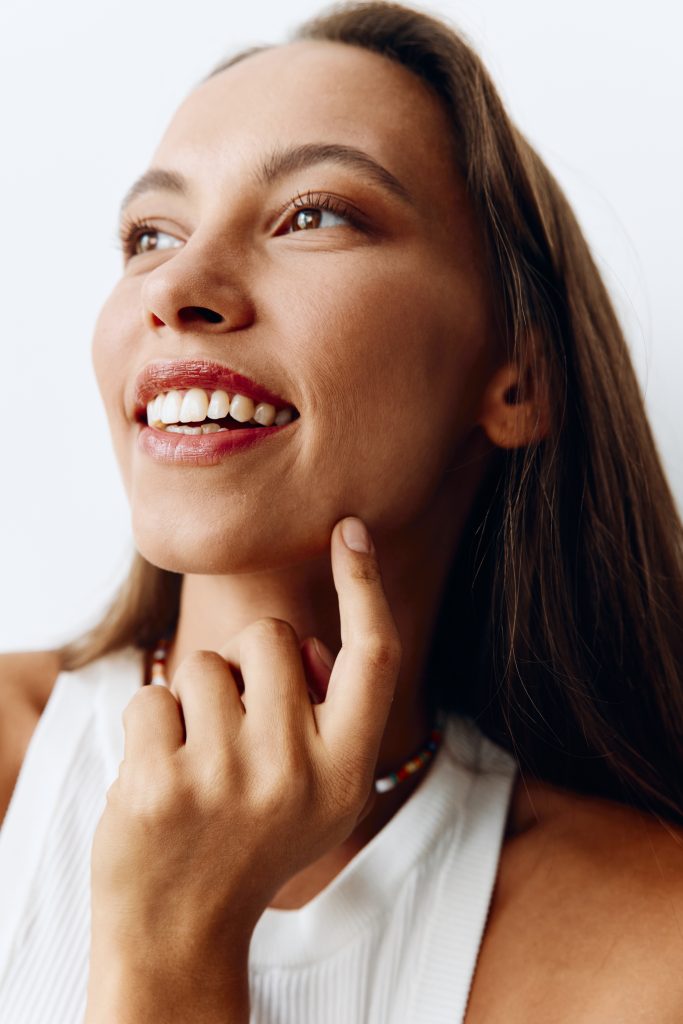 Portrait of a young beautiful woman with tanned skin model on a white background in a white T-shirt with a chain around her neck. High quality photo